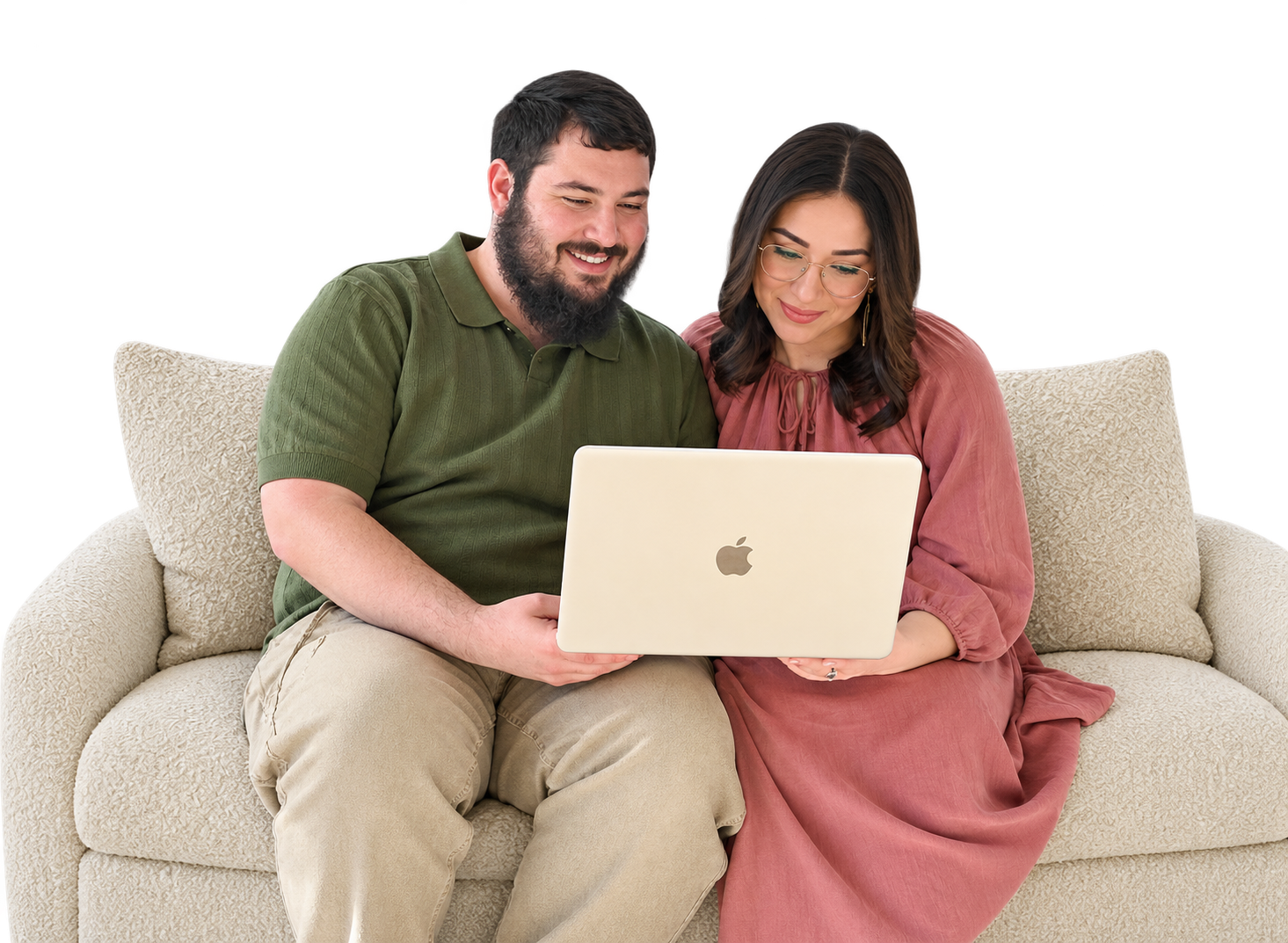 A couple sitting together on an ivory couch looking at a laptop